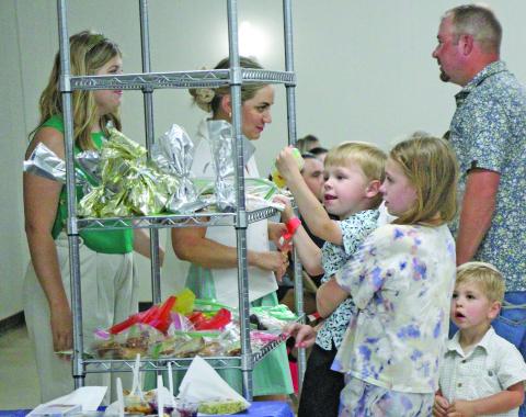Children, at left, used teamwork to help each other pick out their chosen desserts at Holy Cross Catholic School's annual "Bazaar" Sunday, April 27. The event also featured carnival-style games, raffles and a live auction. Sentinel Photo/ Jessica Shepard