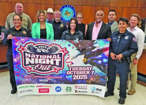 Sentinel Photo/Mike Reddell City officials and city council members join Bay City Police Department officers in showing off a promotional banner for the 2026 National Night Out event Tuesday, Oct. 7. the police-community partnership helps develop bonds between Bay City residents and police officers.