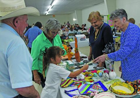 Sentinel Photo/Jessica Shepard A little girl accepts a payment for an item under the watchful eye of her grandfather at the Holy Cross Catholic Church’s annual “Fall Festival and Turkey Dinner” Sunday, Sept. 29, at the Knights of Columbus Hall. The church’s event featured a live auction, raffle, country store, and children’s activities.