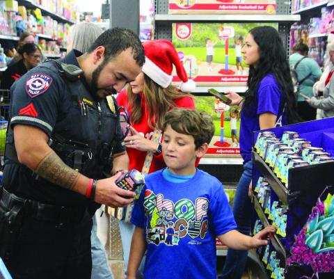 Sentinel Photo/Jessica Shepard A Bay City police officer helps a boy read instructions on a gift during Shop with a Cop at Walmart Dec. 11. More than 40 children benefited from the annual event where Bay City Police Department joins with law enforcement agencies and non-profits from across Matagorda County.