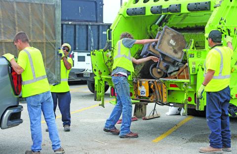 Sentinel Photo/Jessica Shepard GFL Environmental employees work together to unload a truck bed as part of the City of Bay City's "Annual Spring Clean-up" on Saturday, April 25.