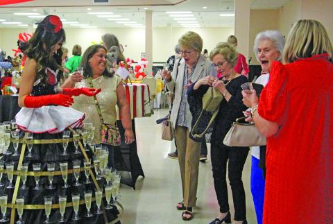 Sentinel Photo/Jessica Shepard Matagorda County Medical Center Foundation "Power of the Purse: Under the Big Top" attendees were greeted by a woman wearing tiers of drinks, left, upon entering the event on Thursday, April 23. Other attractions included a fortune teller and over 100 unique purses and bidding packages to purchase..