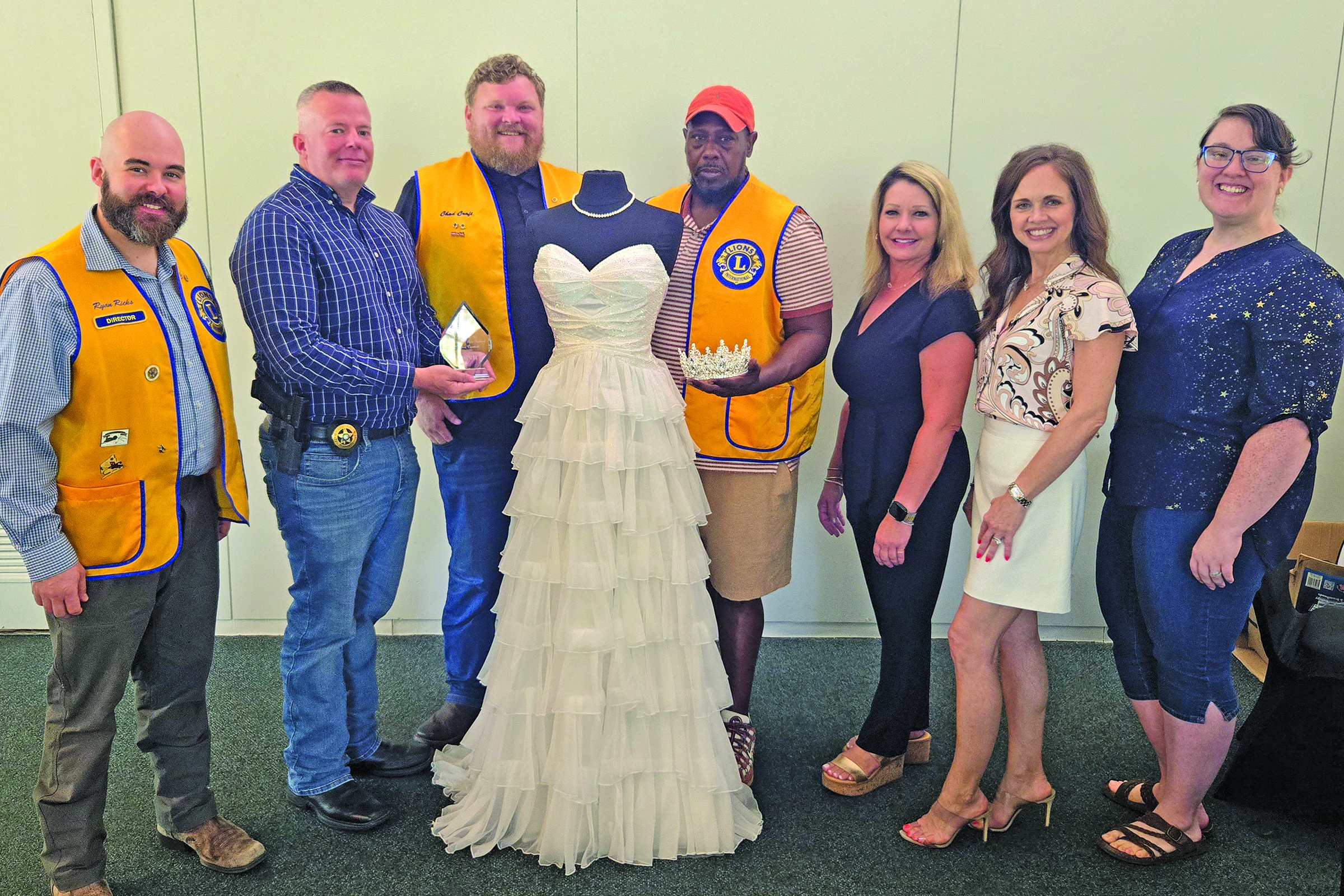 Sentinel Photo/Jessica Shepard Bay City Lions Club members pose with this year's Rice Festival Queen Pageant dress. From left are: Pageant Chairman Ryan Ricks, Festival Chairman Chris Hadash, Club President Chad Craft, and Cory McCray are joined by Green Bros. Jewelers representatives Erin Stone and Amanda Pitard with Pageant Director Rachel Ricks on Aug. 28. The dress and tiara are from El Campo's "New Beginnings Bridal & Prom" while Green Brothers provides the Queen's jewelry.