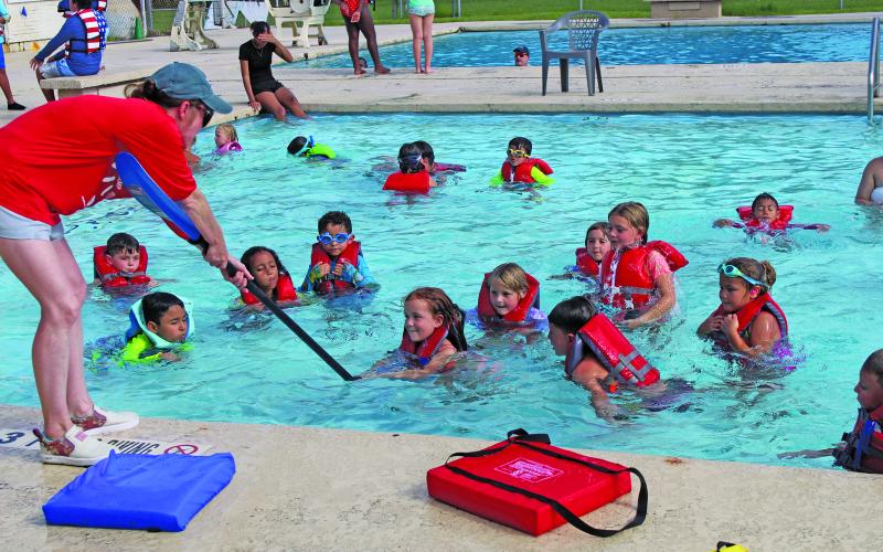 Sentinel Photo/ Jessica Shepard Young swimmers learn from a volunteer how to use a paddle in water rescue.