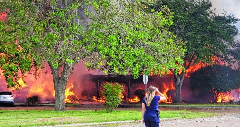 Sentinel photo/Jessica Shepard A Bay City Police Department officer looks on as Taylor Brothers Funeral Home is engulfed in flames, Friday, Oct. 22. The fire lasted three and a half hours and six local volunteer departments responded to the scene. 