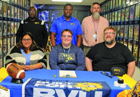 Sentinel photo/Mike Reddell Bay City Blackcat offensive lineman Isaac Allen officially signed with Buena Vista University, Storm Lake, Iowa, in a ceremony last week. Allen, center, is flanked by his parents, Yvette Allen, at left, and his father, Jonathan Allen. His mother is the late Michelle N. Allen. Also a powerlifter, Isaac aspires to become a coach. His coaches, second row from left: are Offensive Coordinator Anthony Smith, Head Coach Robert Jones, Head Powerlifting Coach Ron Arnesen.
