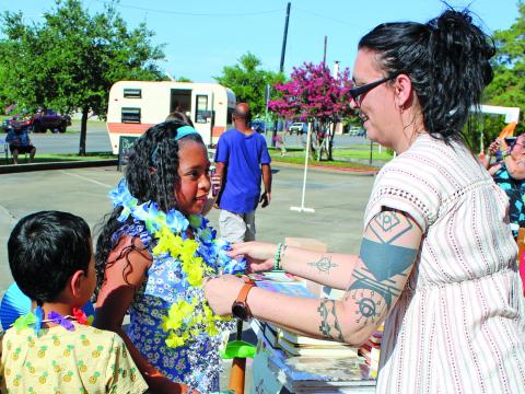 Sentinel photo/Mike Reddell Bay City Public Library's Amanda Garcia, right, hands out an assortment of colored leis as part of the library's "Community Luau" featuring Hiti Mahana Polynesia Thursday, June 23. The luau featured live music, dancing, cake, luau-themed prizes, and free books for children. 