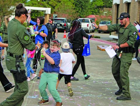 Sentinel photo/Mike Reddell Bay City police officers and others join with kids in the fun spraying Silly String during National Night Out at the Bay City Library Oct. 4.
