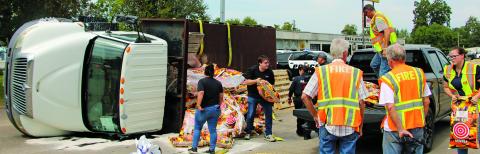 Sentinel Photo/Mike Reddell Bay City police and firefighters help move deer corn sacks from an overturned truck to another truck last week. 