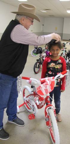 Sentinel Photo/Mike Reddell Sheriff Skipper Osborne places a helmet on a girl who got one of the bikes.