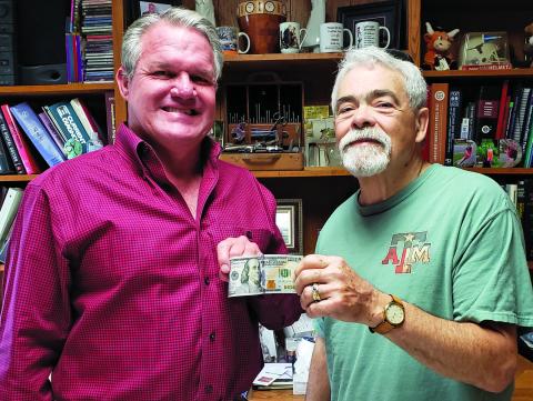 Sentinel Photo/Jessica Shepard Bay City physician Dr. Dane Simons, left, receives a $100 bill from Bay City Sentinel Editor Mike Reddell for being the top prognosticator in the Sentinel’s annual football panel.