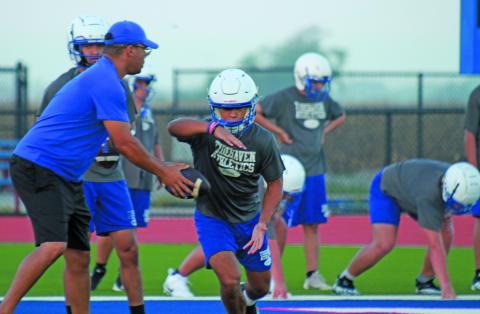 Photo by Anna Hernandez A Tidehaven coach hands off to a Tiger running back during workouts last week. Tidehaven will scrimmpage Shiner at home Friday.