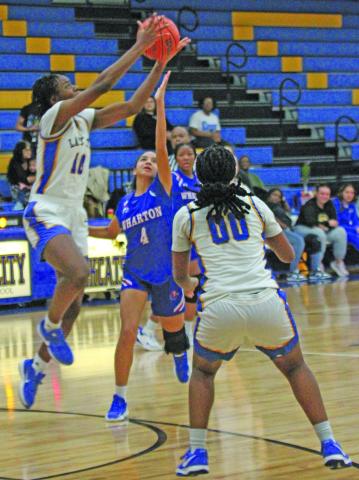 Photo by Anna Hernandez Bay City girls played Wharton here Friday, Feb. 6. Above, Lady Cat junior center Sasha Orwucheknia goes up high to battle Wharton players. Senior Kam Davis (00) positions herself to help.