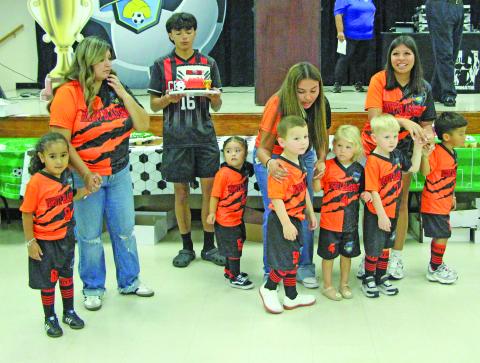 Sentinel Photo/Jessica Shepard Bay City Youth Soccer Club's "Opening Ceremony & Cake Auction" featured over 40 cakes and teams on deck to kick off the fall season on Sept. 8. Seen here are the "Mighty Blasters" attempting to incite higher bids from the crowd.