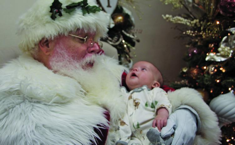 Sentinel photo/Mike Reddell Infant RJ Lane casts a wondrous look at Santa at Nia’s Towne Square Restaurant downtown Friday, Dec. 17.