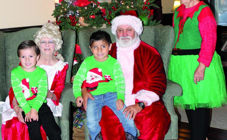 Sentinel photo/MaLinda Reddell Mr. and Mrs. Santa Claus and helper visited with two boys, Saul and Matea Garcia, at the Blessing Hotel’s annual Santa stopover Dec. 8.