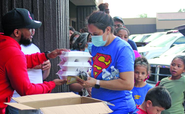 Sentinel photo/Jessica Shepard Desmond "Huncho" Sandles, left, hands out turkey dinner plates at Big Homie's Wings, Rings & Stuffed Baked Potatoes restaurant Saturday, Nov. 20. The event also featured free turkey vouchers sponsored by HEB and distributed by "Growing Into Men Of Standard" for families with youth males ages 5-18 in their households.