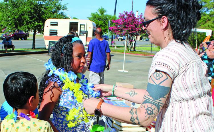 Sentinel photo/Mike Reddell Bay City Public Library's Amanda Garcia, right, hands out an assortment of colored leis as part of the library's "Community Luau" featuring Hiti Mahana Polynesia Thursday, June 23. The luau featured live music, dancing, cake, luau-themed prizes, and free books for children.