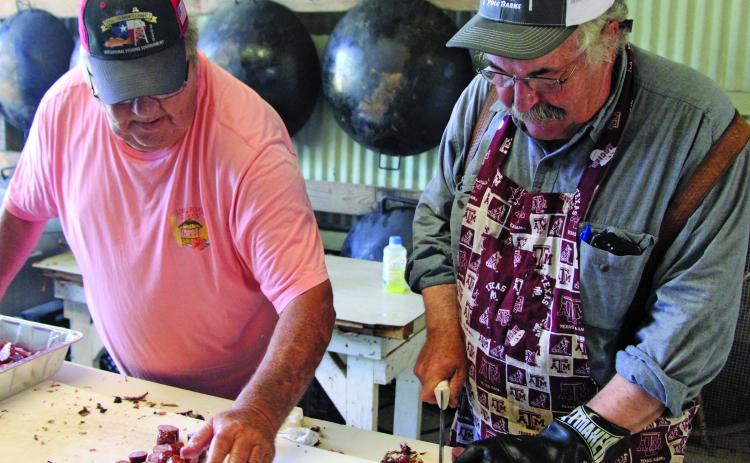 Sentinel photo/Mike Reddell Tom Klaiber, left, helps George Deshotels chop up sausage for the annual Matagorda Volunteer Fire Department barbecue fundraiser Saturday, May 28.
