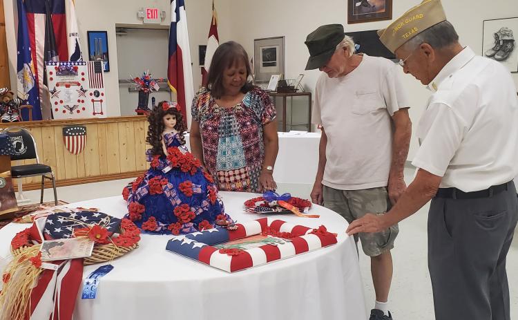 Sentinel photo/MaLinda Reddell VFW Post 1428 member Ken Thames, right, gives Jeanne and Roland Fondon of Bay City a history Sunday, Aug. 14, of the Buddy Poppy and the exhibit that’s was on display at the post.