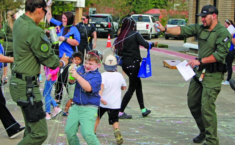 Sentinel photo/Mike Reddell Bay City police officers and others join with kids in the fun spraying Silly String during National Night Out at the Bay City Library Oct. 4.