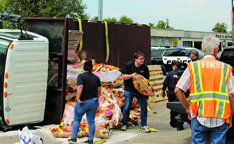 Sentinel Photo/Mike Reddell Bay City police and firefighters help move deer corn sacks from an overturned truck to another truck last week.