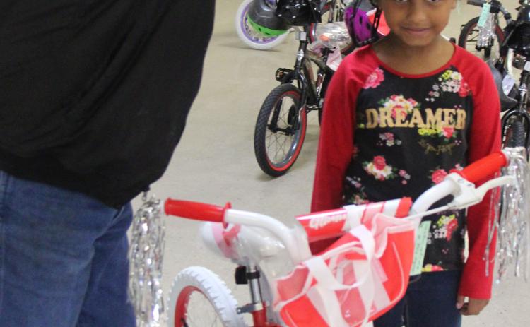 Sentinel Photo/Mike Reddell Sheriff Skipper Osborne places a helmet on a girl who got one of the bikes.