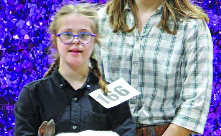 Chelsea Riccio shows her meat pen rabbit "Scratches" off to potential buyers at the Matagorda County Fair and Livestock Association's annual "Junior Livestock Auction" Saturday, March 4. Riccio's older sister Lavery lends a hand while bids are made.  Sentinel Photo/MaLinda Reddell