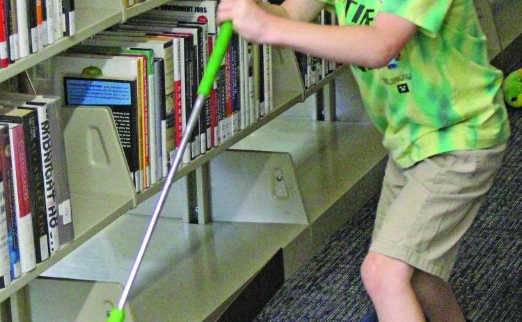 Families gathered to try their hand at the Bay City Public Library's annual "Mini Golf" event Monday morning. Children and adults of varying ages took shots through winding fairways and obstacles ranging from stuffed snakes and space shuttles to angled tracks and corkscrew ramps. Sentinel Photo/ Jessica Shepard