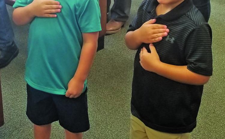 Commissioner Mike Estlinbaum’s grandsons, Connor (left) and Luke, lead the court’s pledges. Sentinel Photo/Mike Reddell