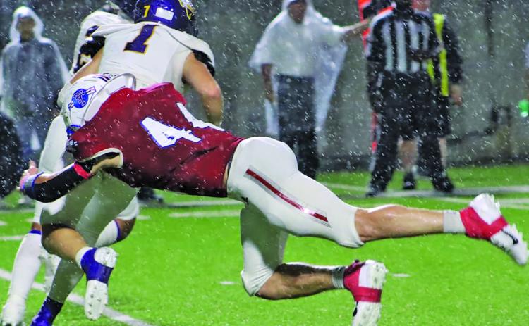 LeDarion Stone/Live in the Moment Photography Tidehaven defensive End Justin Griffith (44) makes a diving tackle on a Buffalo running back in the driving rain.