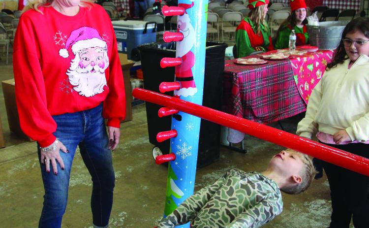 Gena Lea Smith, Van Vleck High School’s Theater Director, laughs watching a boy’s successful maneuver under the limbo bar at Bay City's annual Santa's Fly-In event Dec. 11, at Bay City Regional Airport. It was a free, festive morning with storytime, milk & cookies. Bay City Public Library, Bay City Regional Airport, and Van Vleck Leopard Players partnered in the event. Sentinel Photo/Mike Reddell