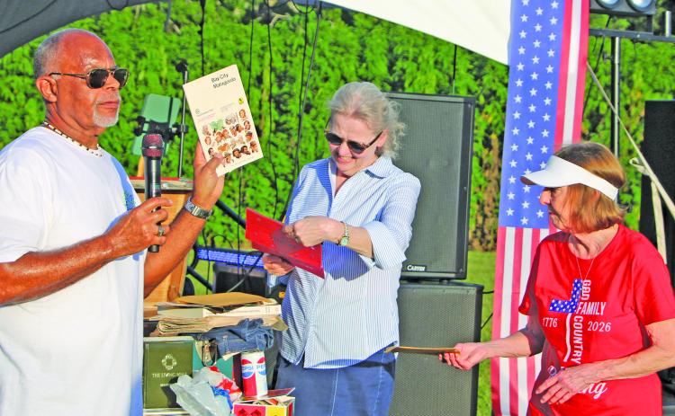 Sentinel Photo/Mike Reddell Bay City Mayor Robert Nelson holds up a 1976 phone book taken from the time capsule that he, Matagorda County Museum Director Cynthia Armstrong and Museum Archivist Jennifer Bishop opened earlier during ceremonies at the city’s LeTulle July 4 events.